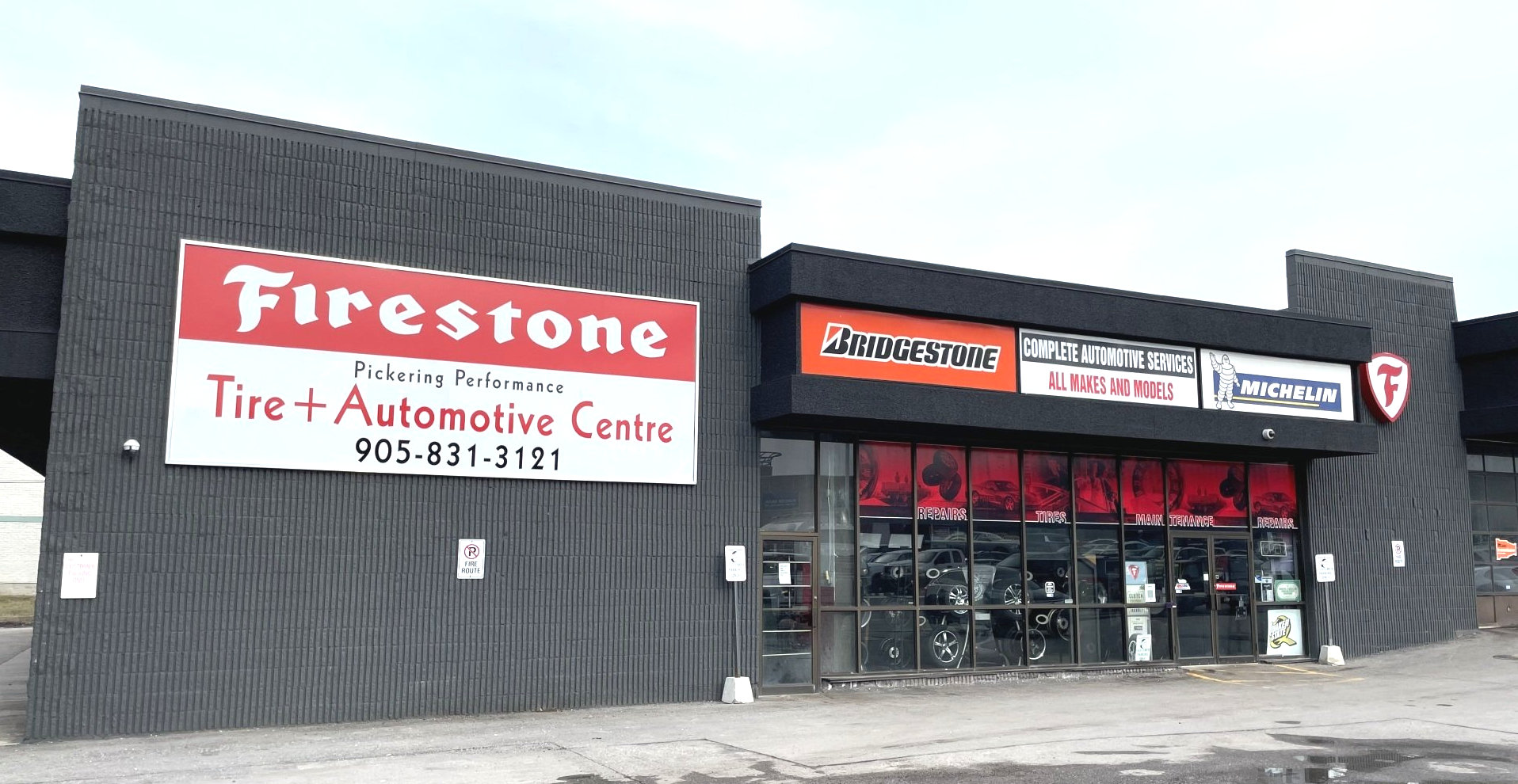 Exterior of a Firestone Tire and Automotive Centre in a black building with red signage.
