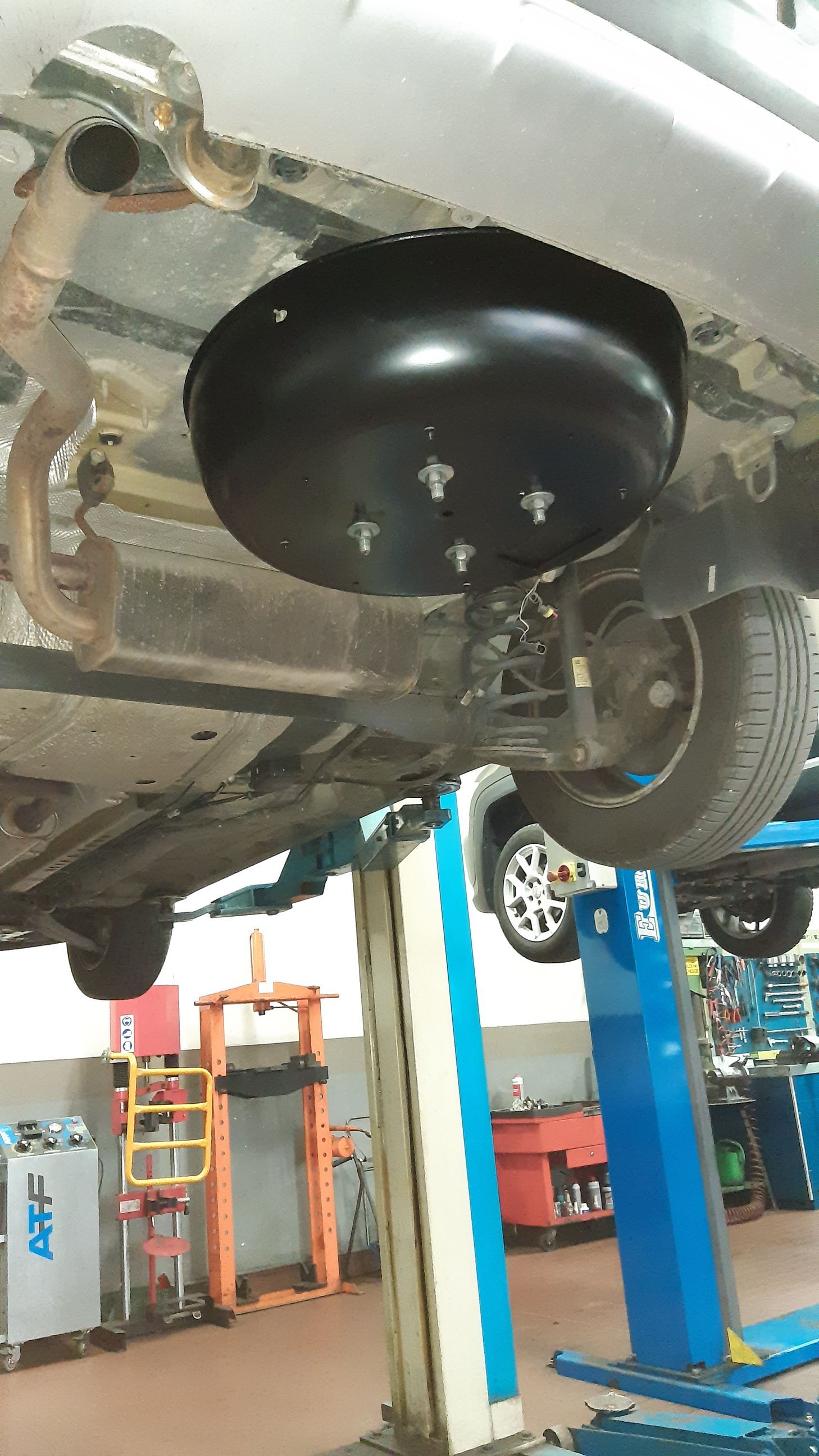 Un'auto è parcheggiata su un ponte sollevatore in un garage.