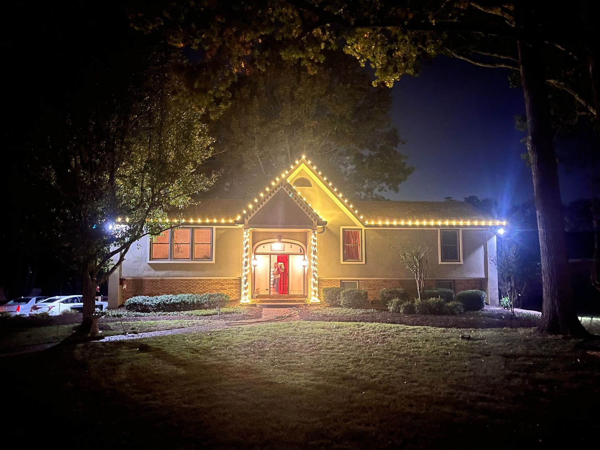 A house with christmas lights on it is lit up at night.