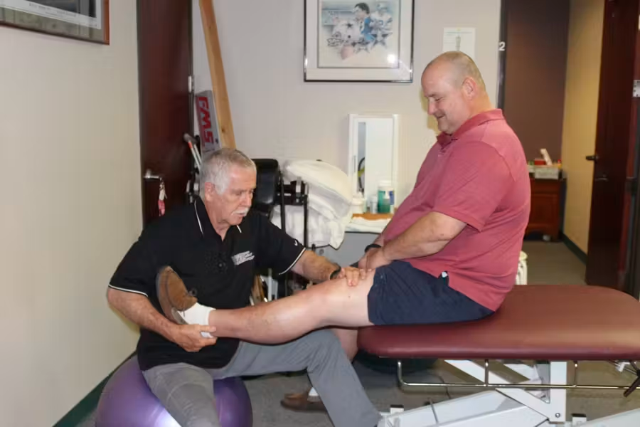 Physical therapist stretching a patient’s leg on a treatment table in a clinic room