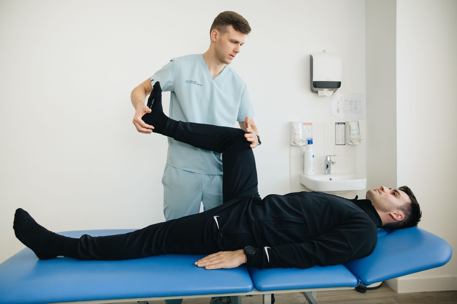 Physical therapist stretching a patient’s leg on a treatment table in a clinic.