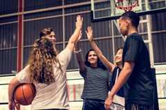 Three people high-five on an indoor basketball court, with one holding a basketball.