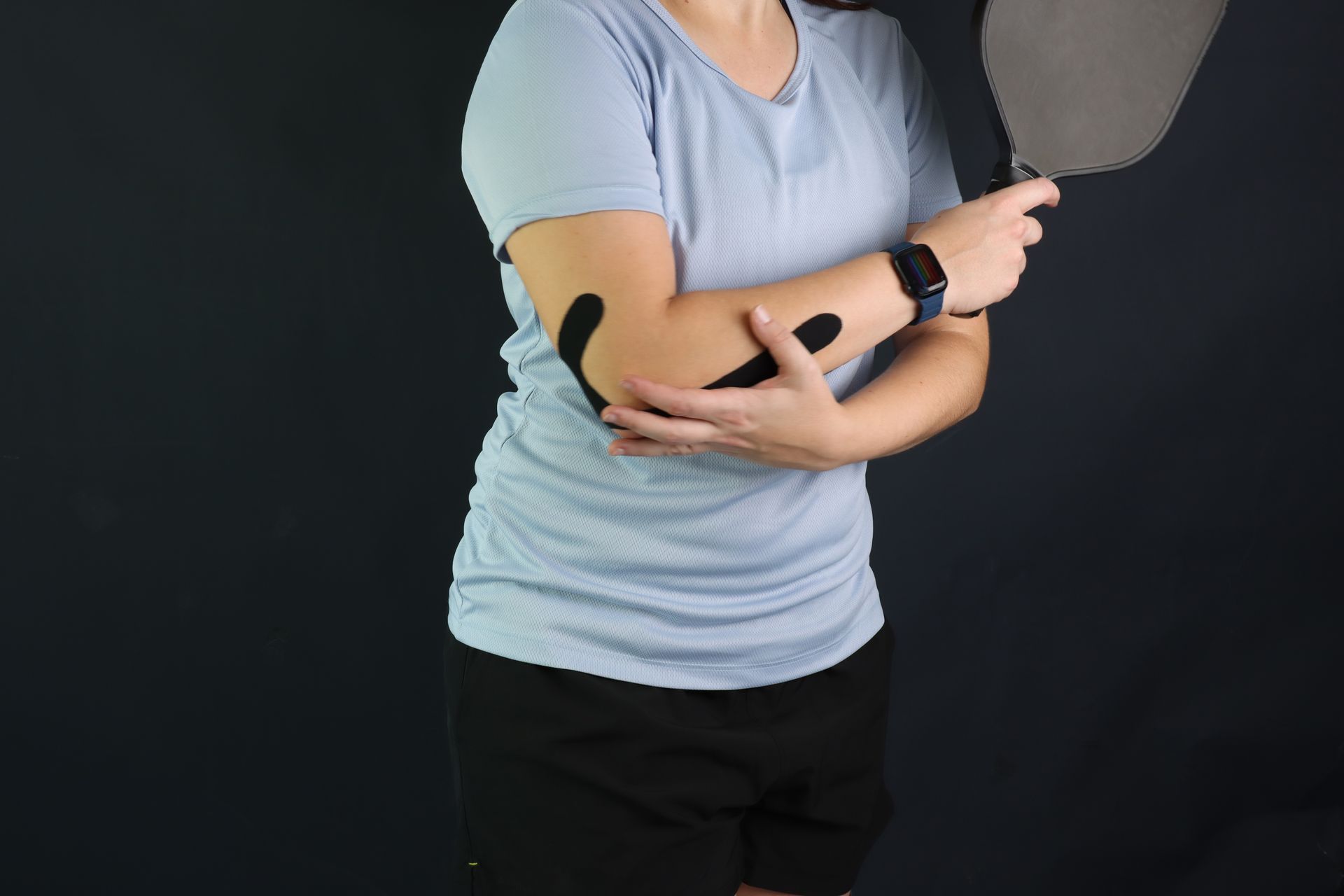 Person in a light blue shirt gesturing with crossed arms against a dark background