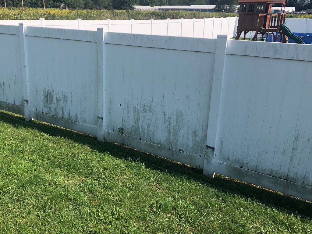 A white fence is sitting in the middle of a lush green field.