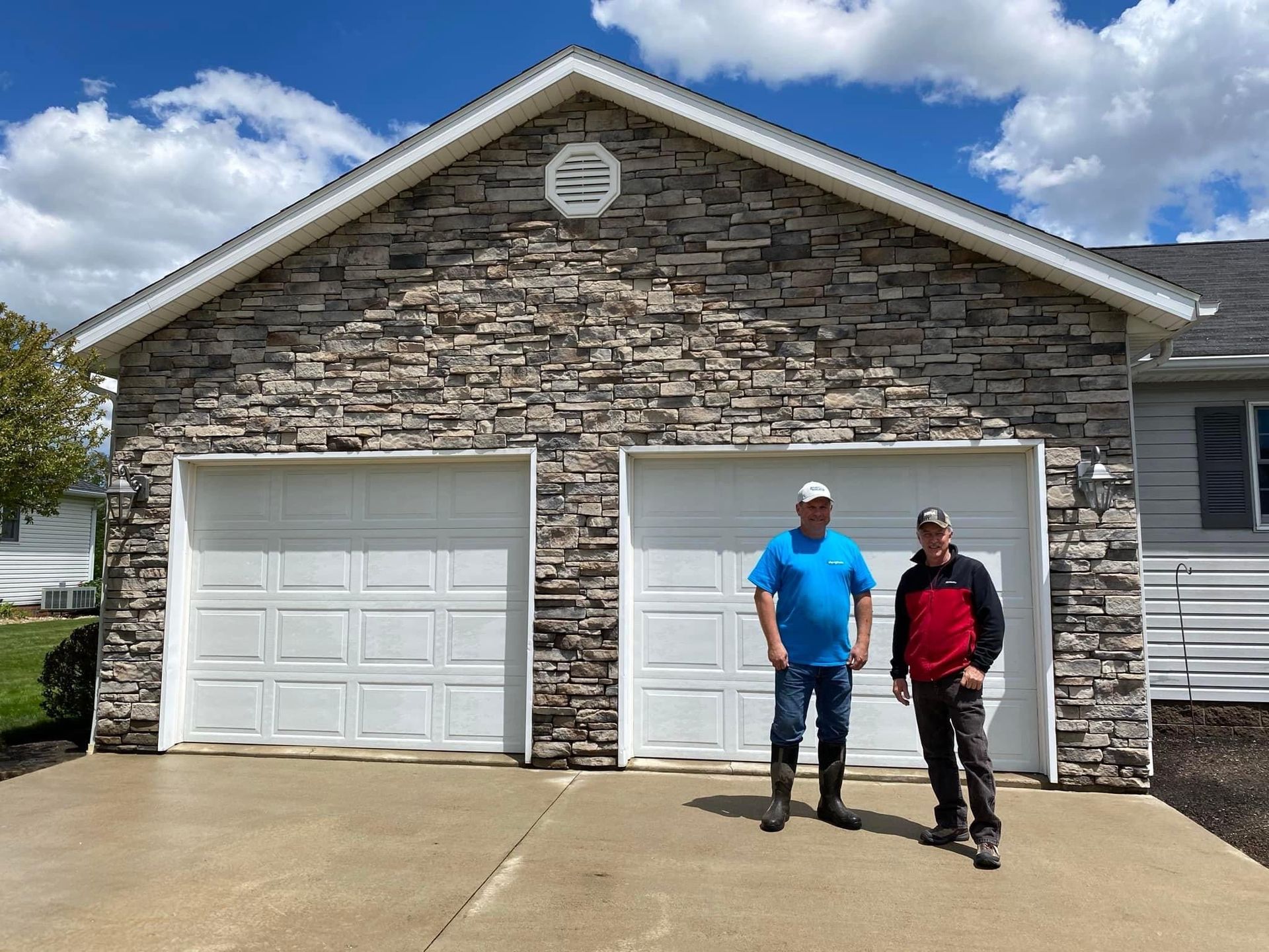 Two men are standing in front of a garage door.
