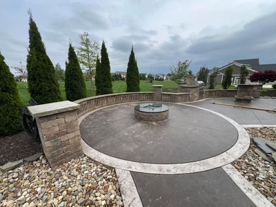 There is a fire pit in the middle of the patio surrounded by rocks.