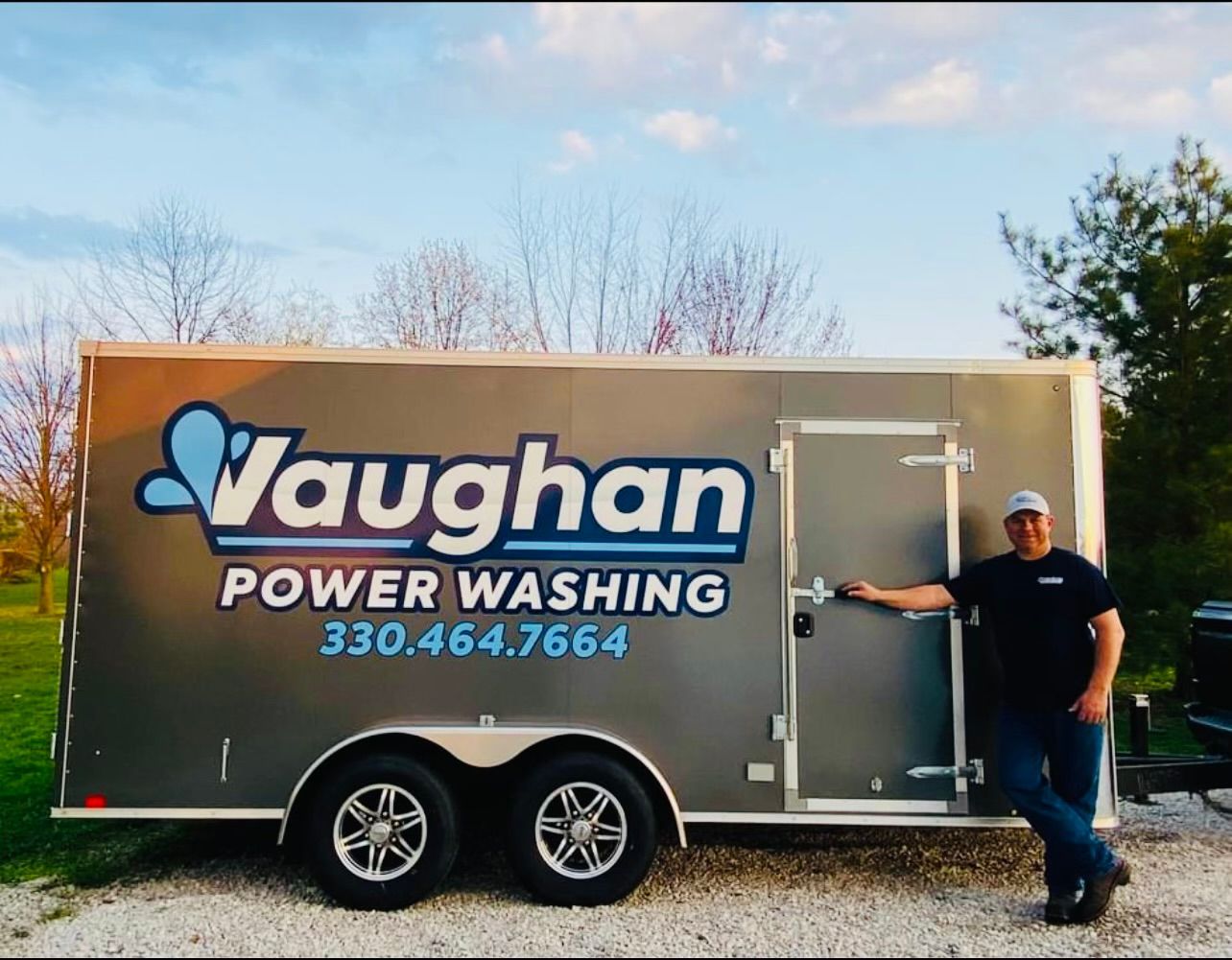 A man is standing in front of a trailer that says vaughan power washing
