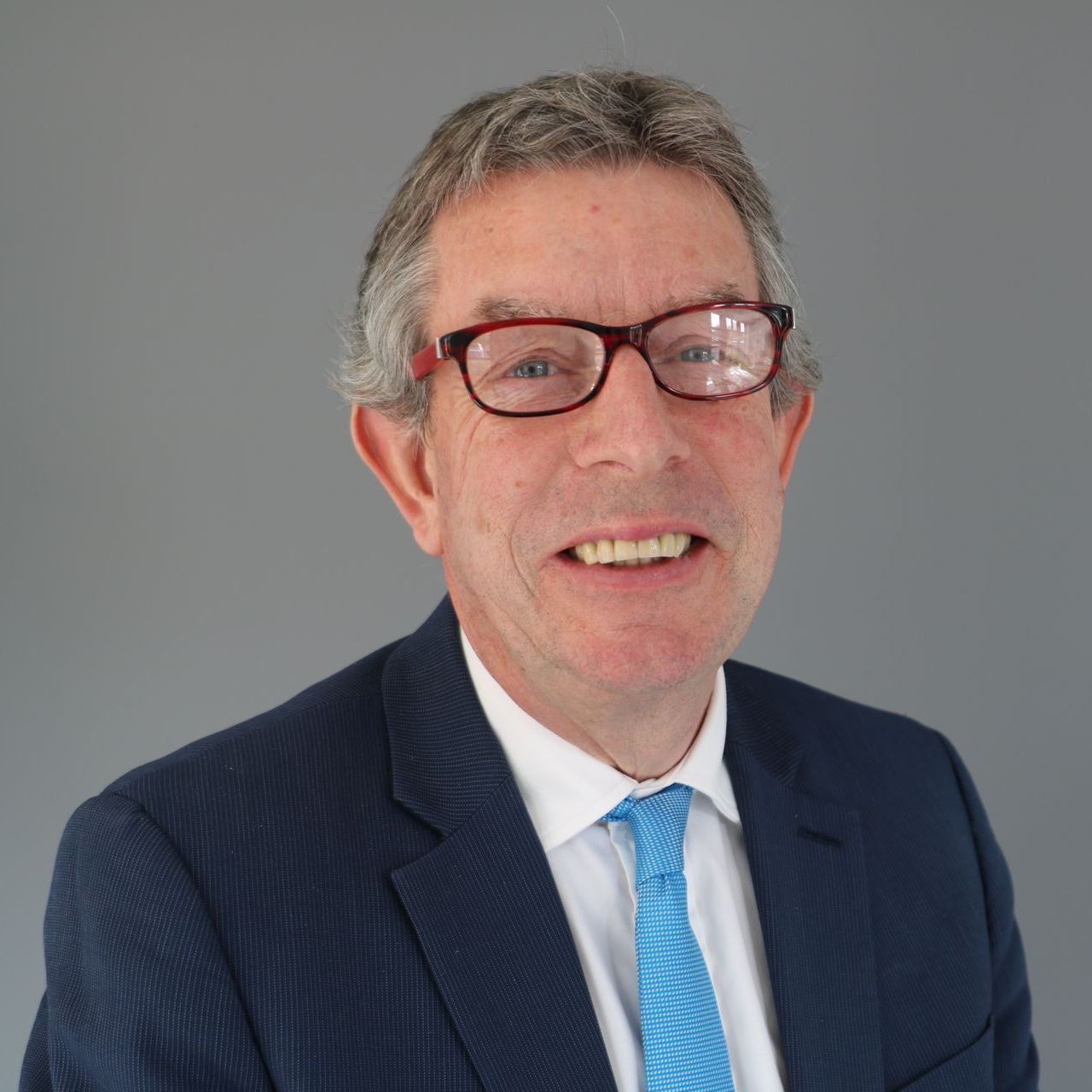 A man in a suit and tie is smiling for the camera.