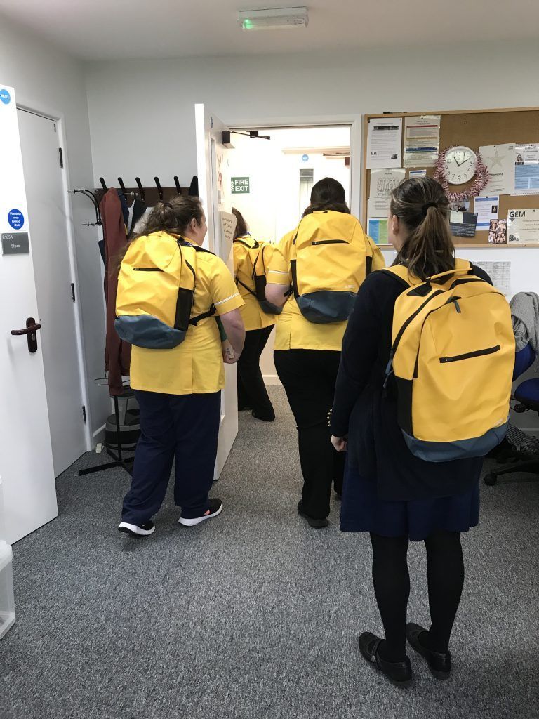 A group of people wearing yellow backpacks are walking through a room.
