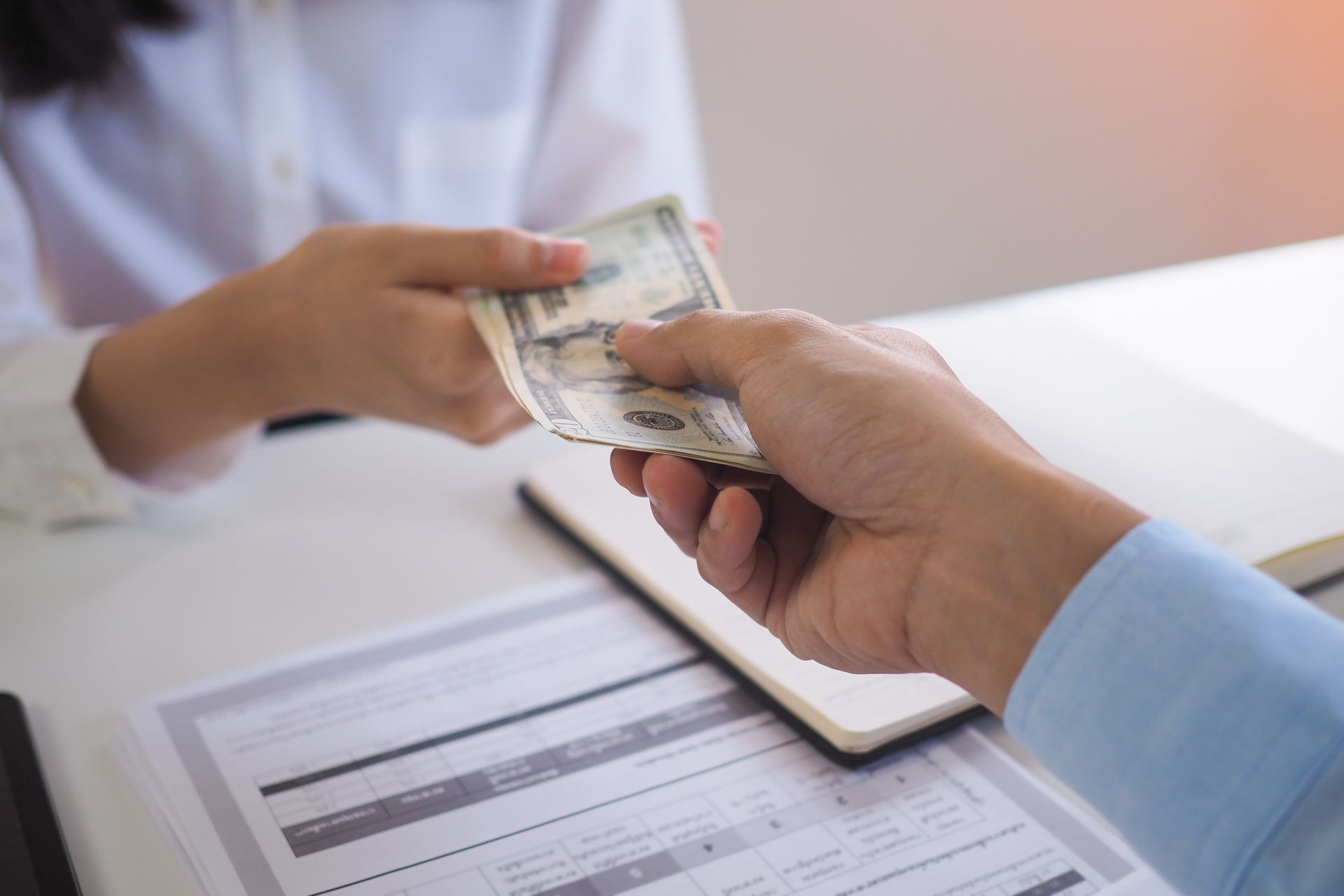 A lender hands cash to an individual for a personal loan.
