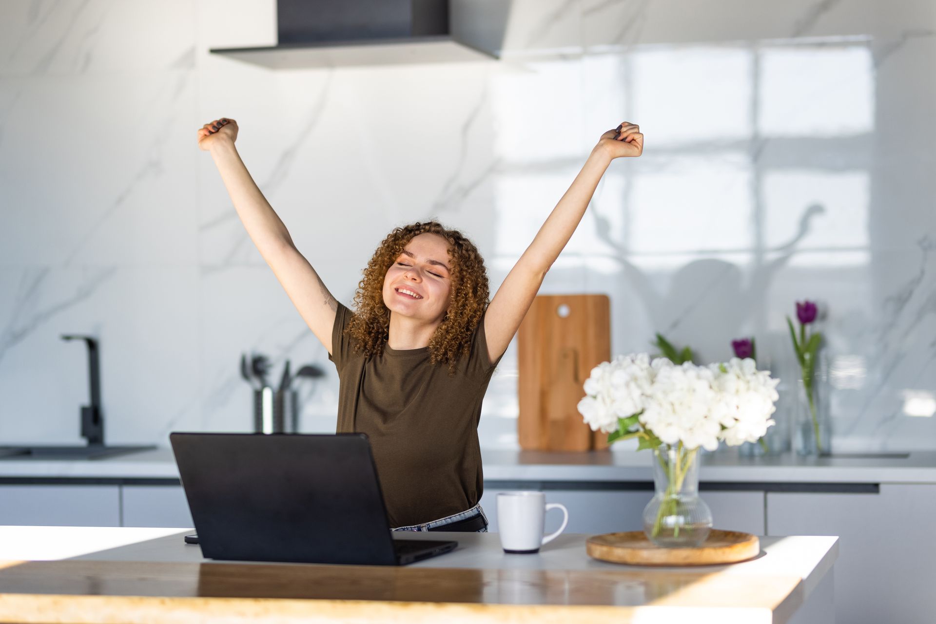 A happy woman behind her laptop is celebrating after getting her emergency personal loan approved.