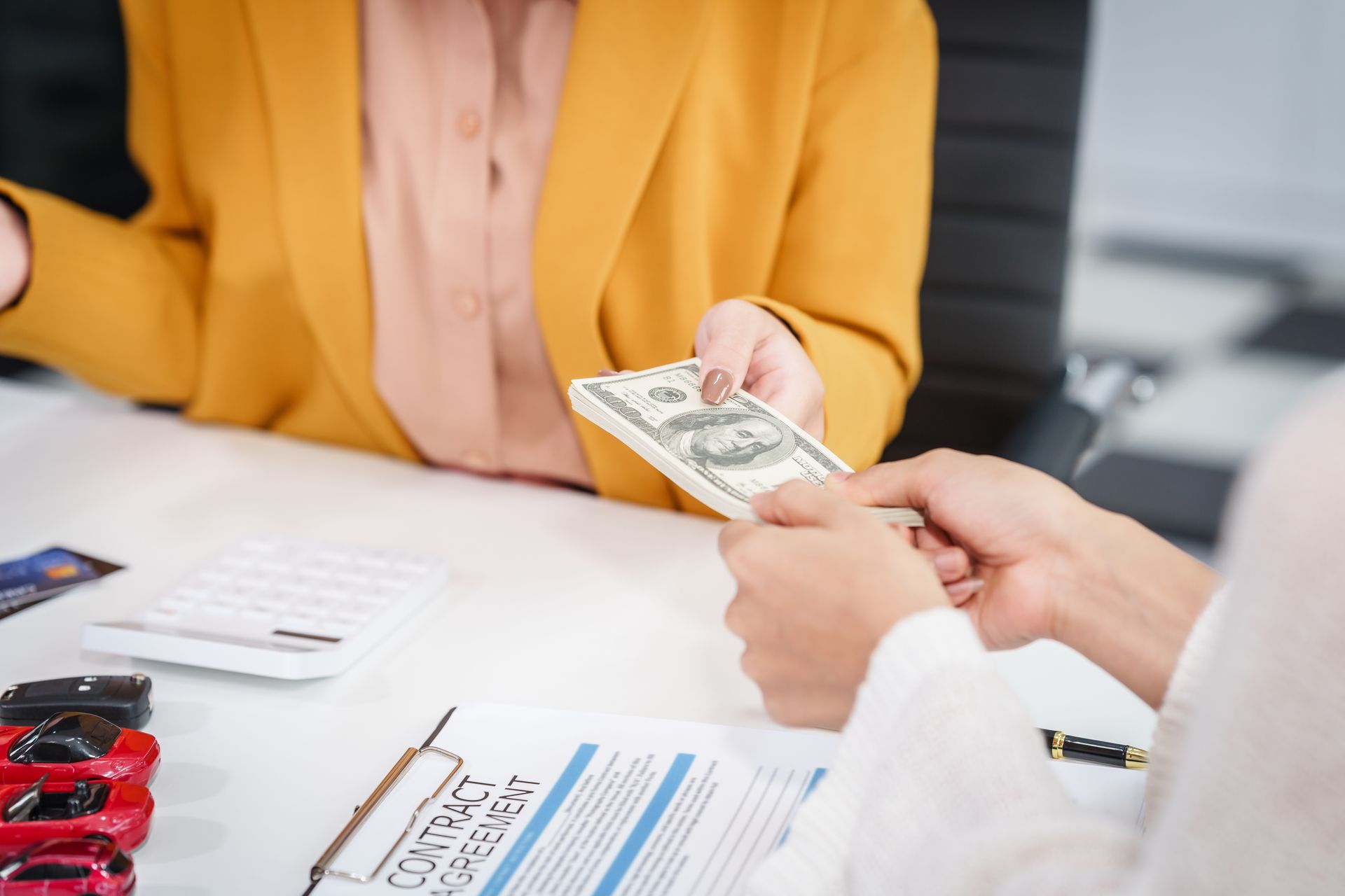 Personal cash loans: handing over cash after signing a contract agreement at the desk.