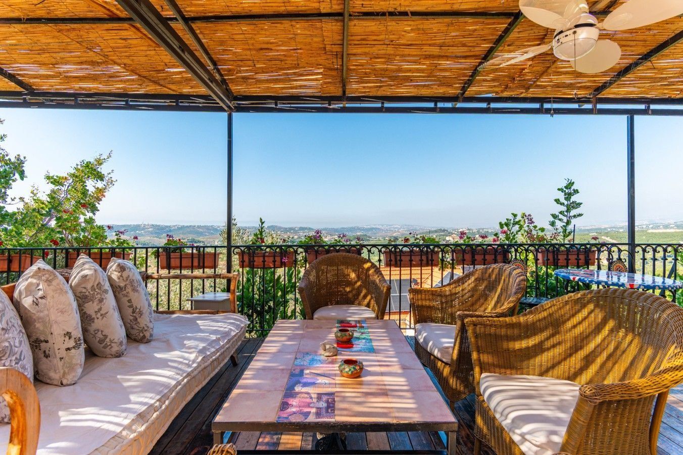 Shaded terrace with cane roof and wicker armchairs looking over the valley at Villa Bridi, Batroun Hills, Lebanon