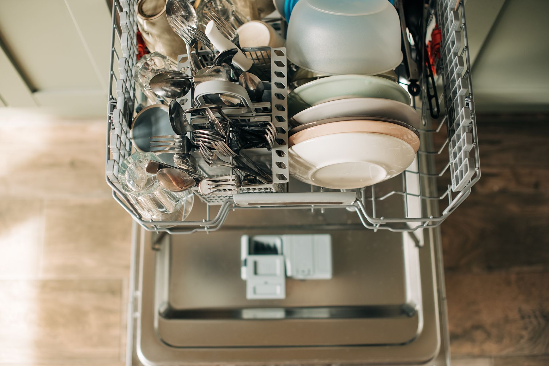 A dishwasher filled with plates , bowls , utensils and glasses.