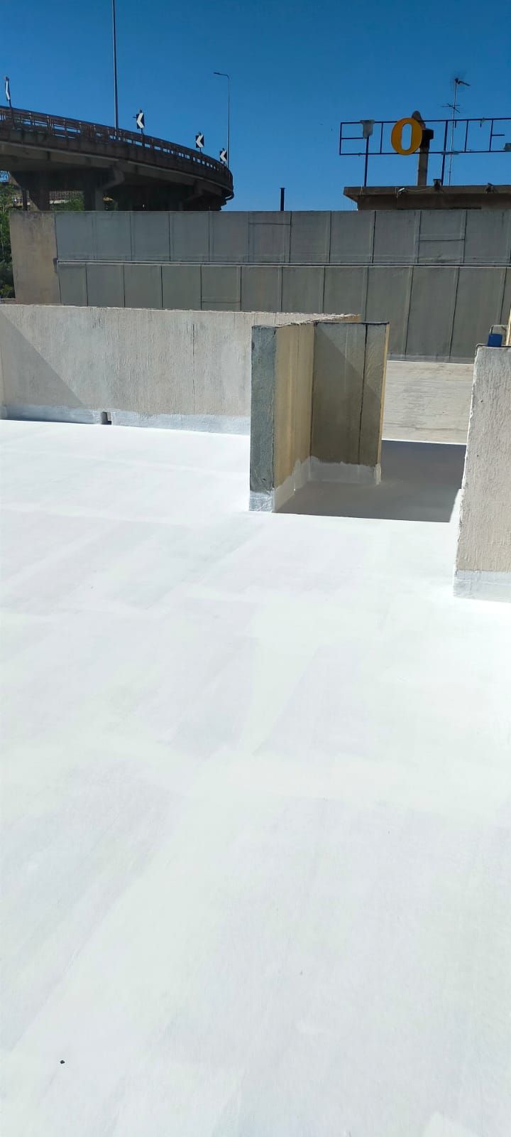 Tetto bianco con pareti in cemento e cielo azzurro sopra.