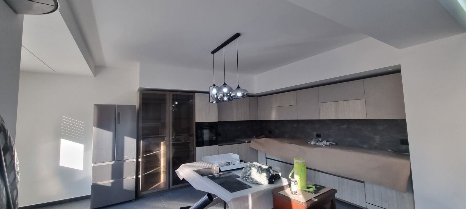 Cucina moderna con mobili, ripiani e lampada a sospensione.