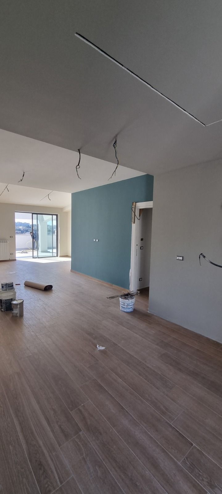 Costruzione degli interni: pavimento in legno, parete decorativa color verde acqua, pareti bianche e cavi elettrici a vista.