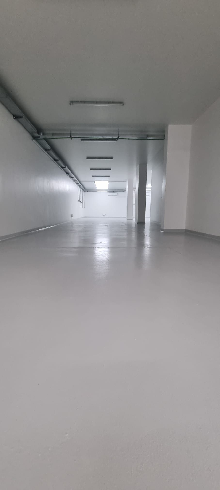 Stanza vuota, con pareti bianche, pavimento lucido e luci soffuse.