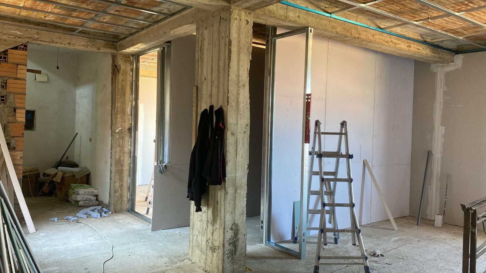 Interno durante la costruzione con mattoni a vista, cartongesso e una scala.
