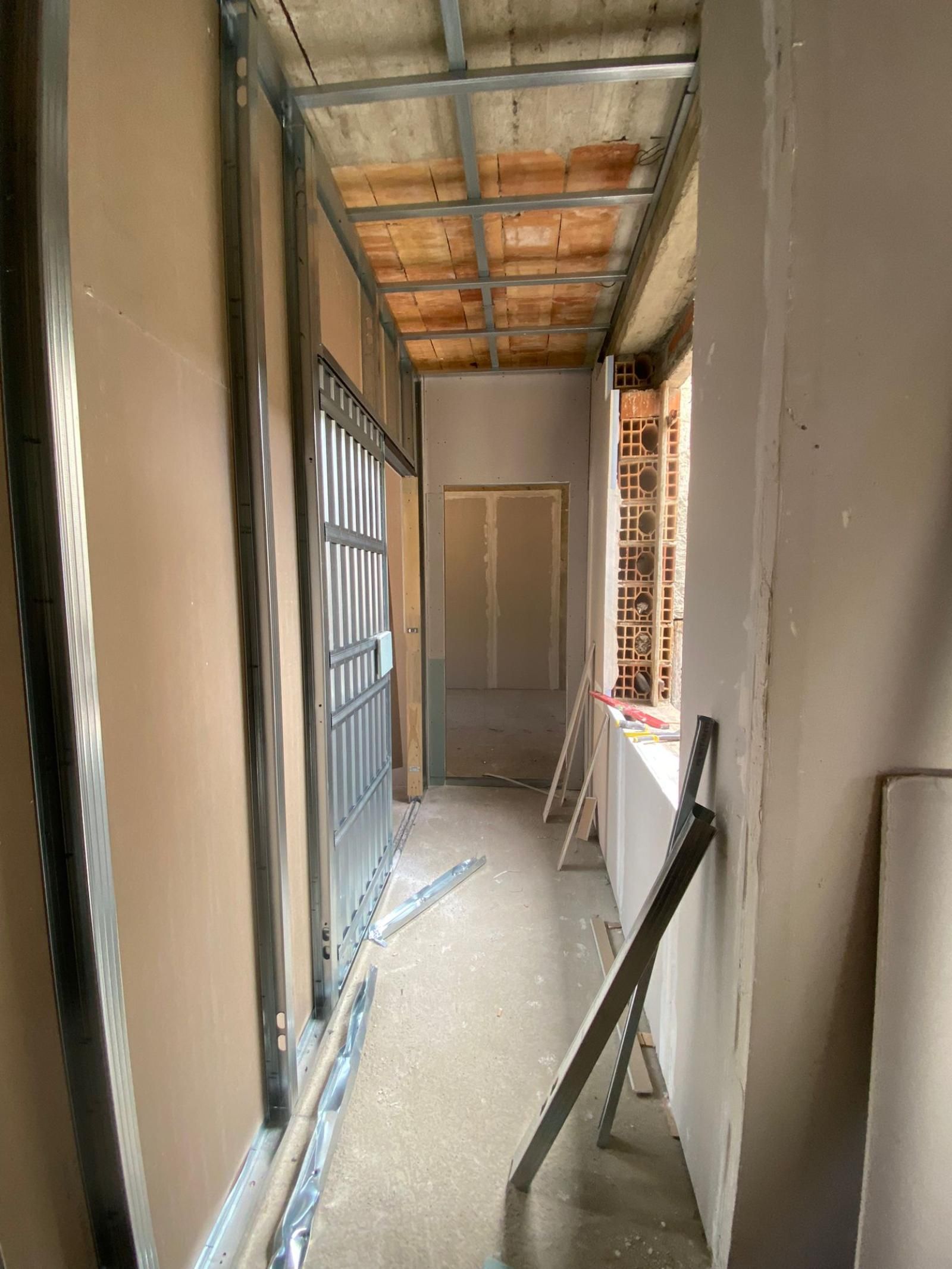 Interni: corridoio con struttura in metallo, cartongesso e soffitto parzialmente a vista. Tonalità marrone chiaro e beige.