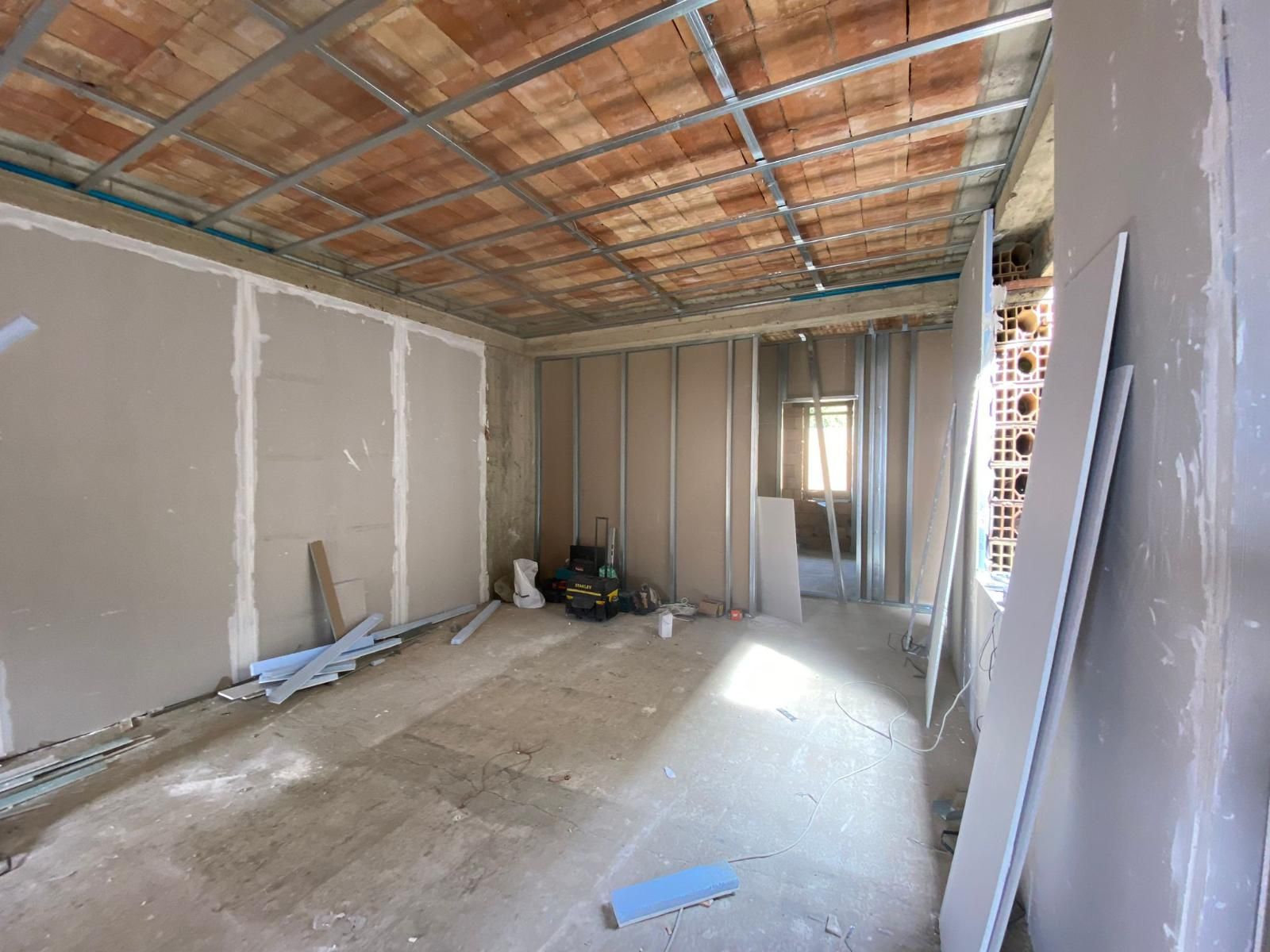 Stanza interna in costruzione con cartongesso e travi a vista sul soffitto.