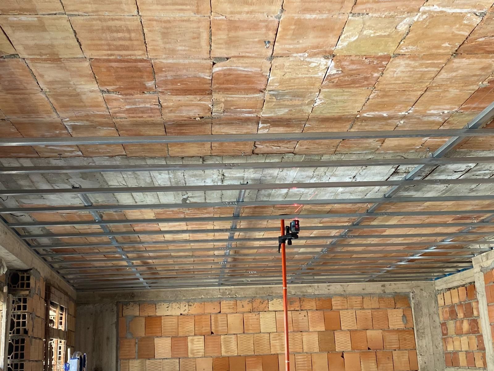Vista interna di un edificio incompiuto con soffitto in mattoni a vista e travi di sostegno in acciaio.