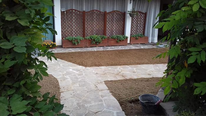 Sentiero del giardino che conduce a un patio con piante in vaso e arbusti che incorniciano il panorama
