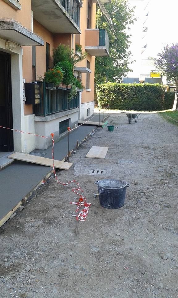 Passerella pedonale del condominio in costruzione con ghiaia, lastre di cemento, secchi e attrezzi accanto all'edificio