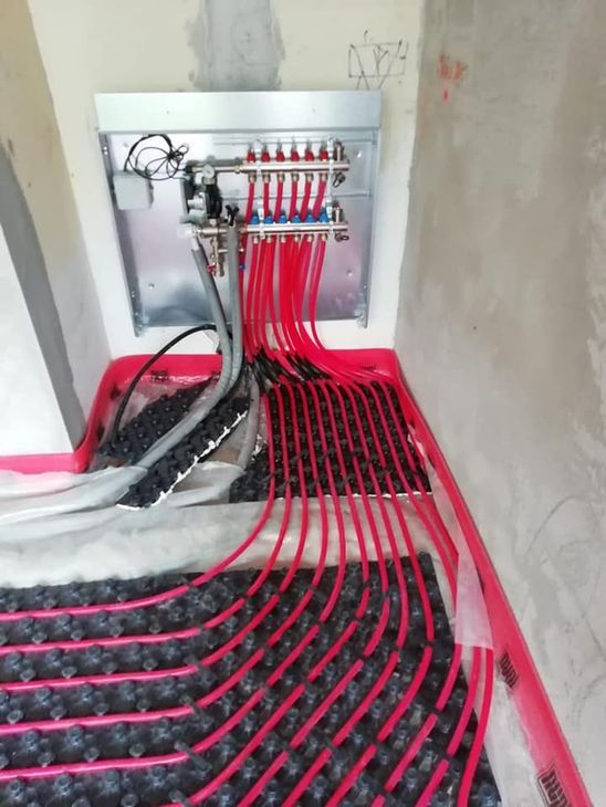 Quadro elettrico con numerosi cavi rossi instradati attraverso un'apertura nel muro di un cantiere.
