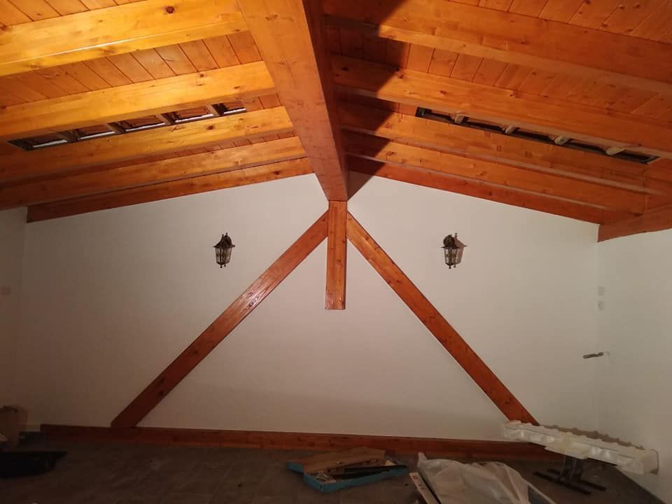 Interno della mansarda con travi a vista in legno e pareti bianche.