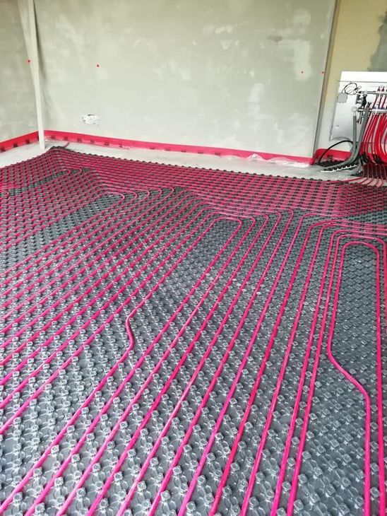 Il pavimento interno della stanza era ricoperto da tubi di riscaldamento a pavimento rosa e neri prima dell'installazione.