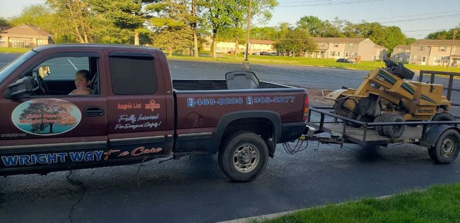 A truck is towing a stump grinder on a trailer.