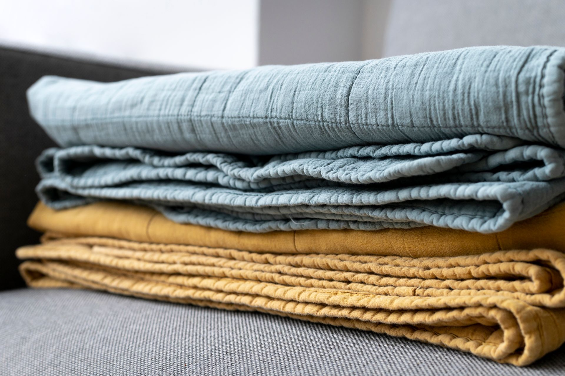 Stack of folded blue and mustard towels on a gray surface