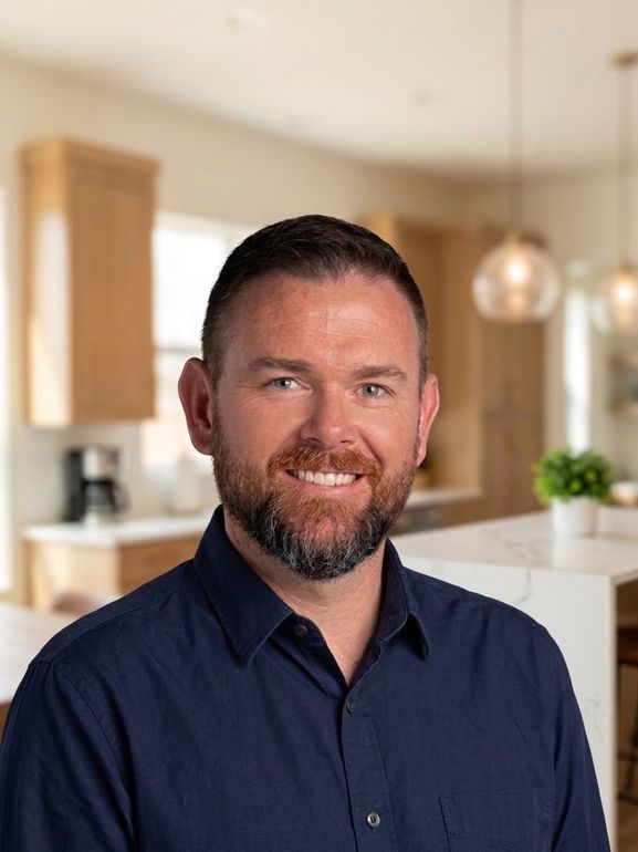 Smiling man in a navy shirt against a blurred indoor background