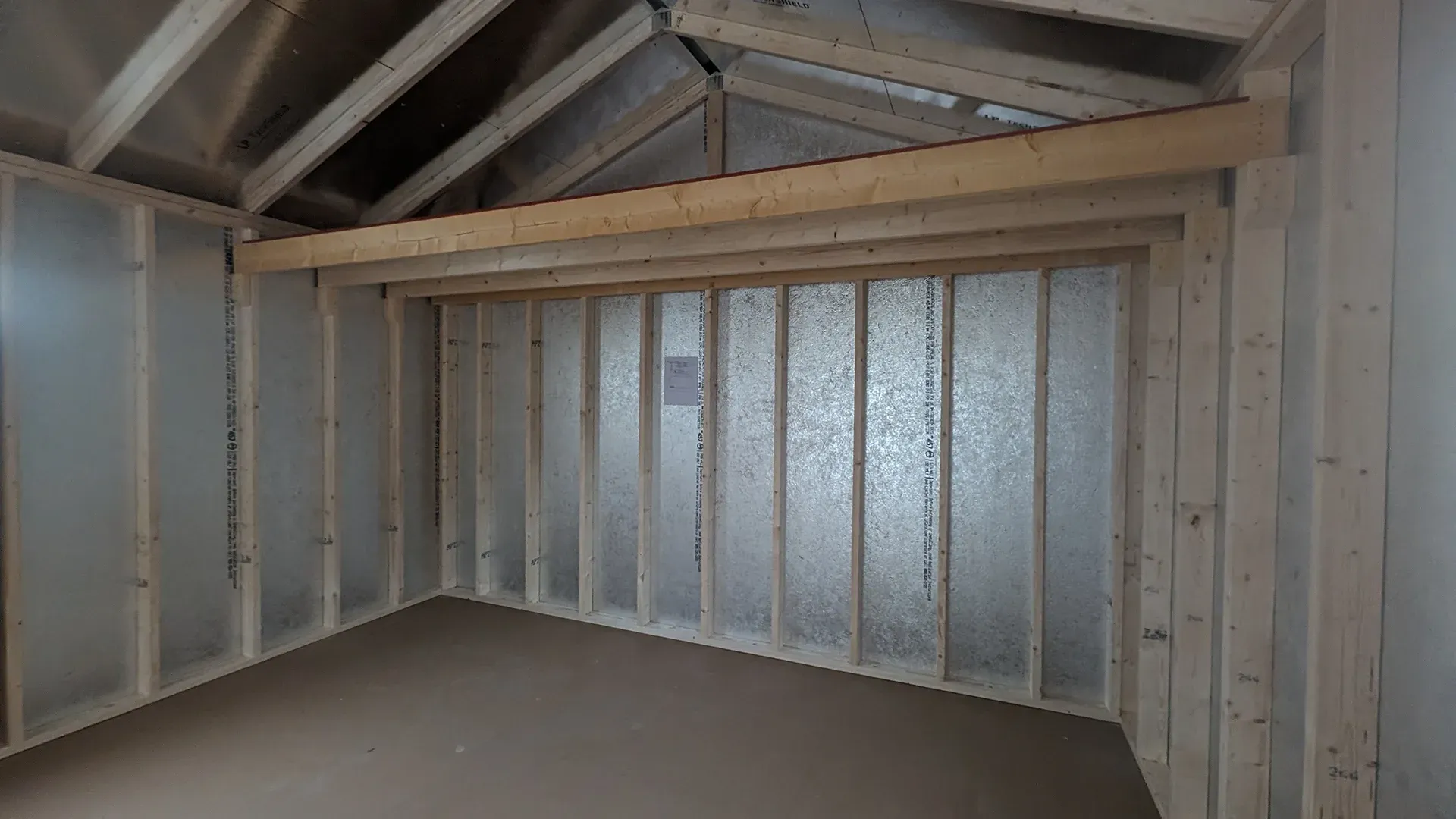 Interior of a shed under construction. Wood framing and insulation are visible.