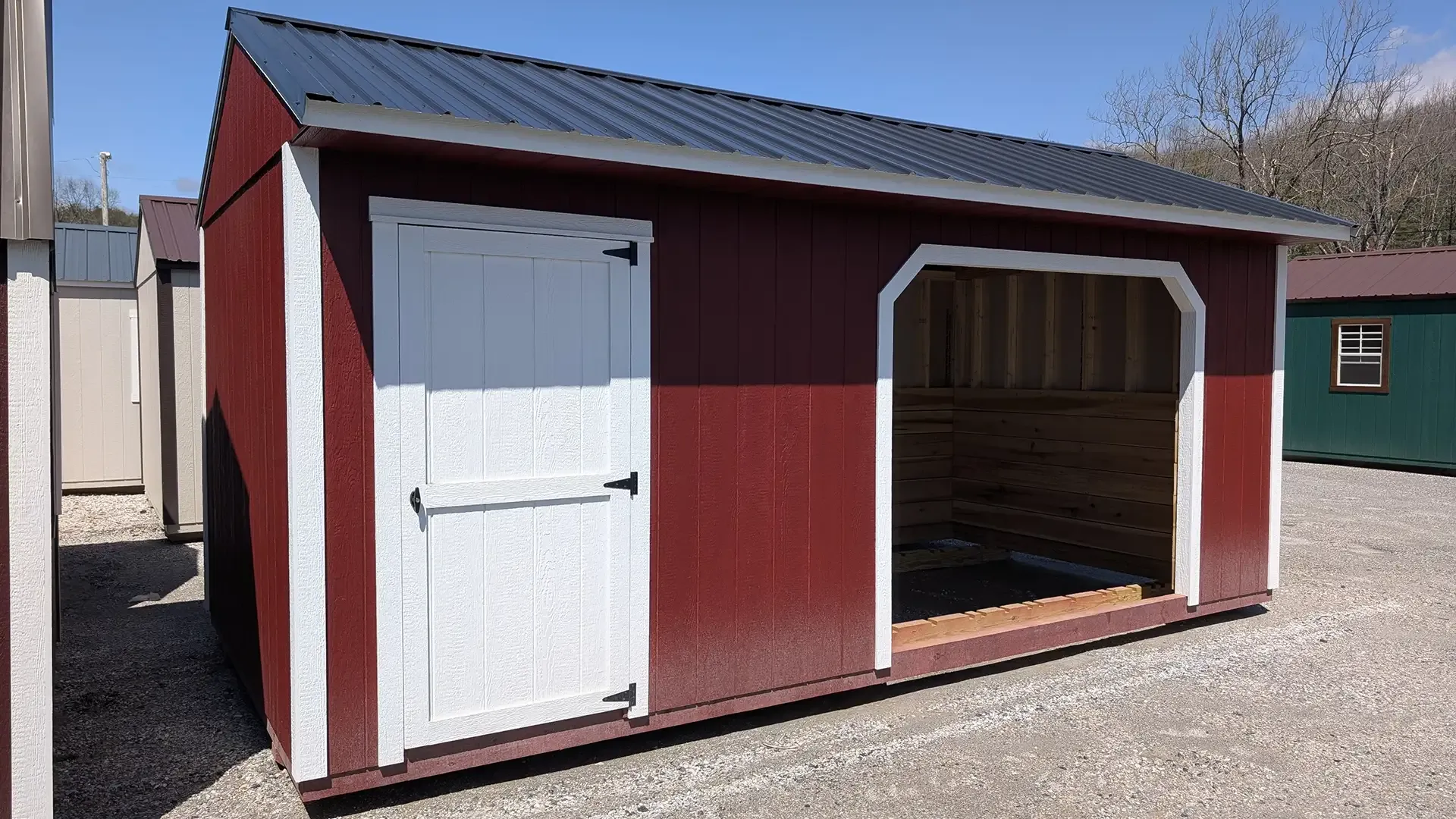 Red shed with white trim and door, black roof, and open entry.