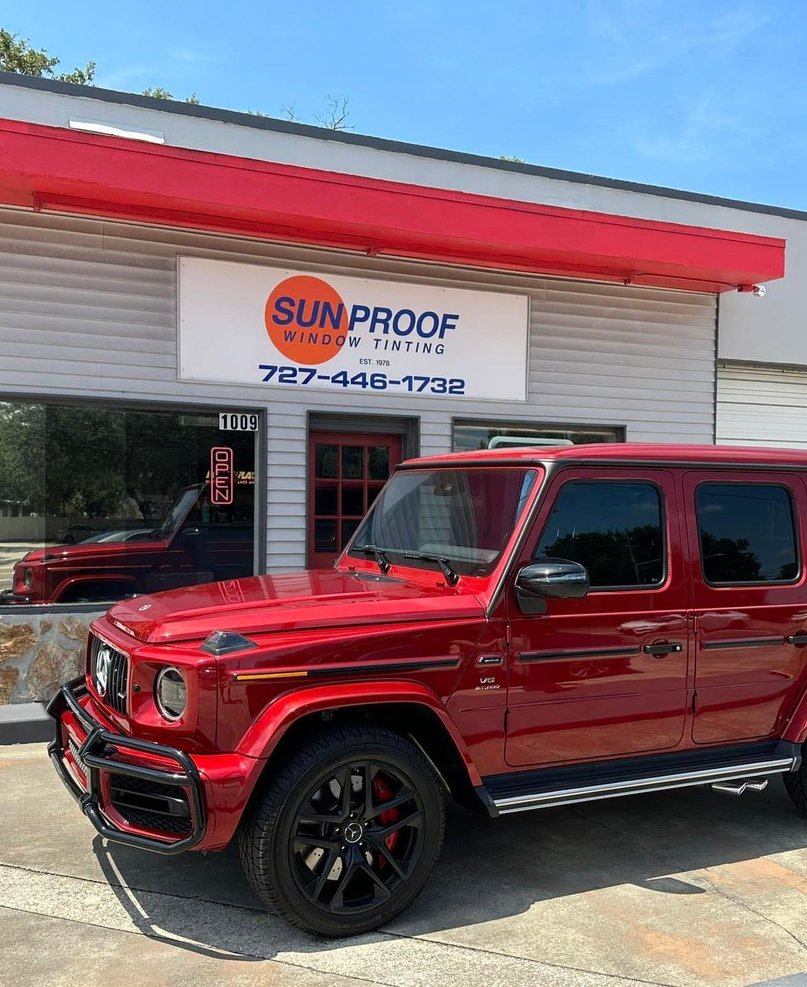 Red SUV parked outside Sunproof with red awning and open garage door