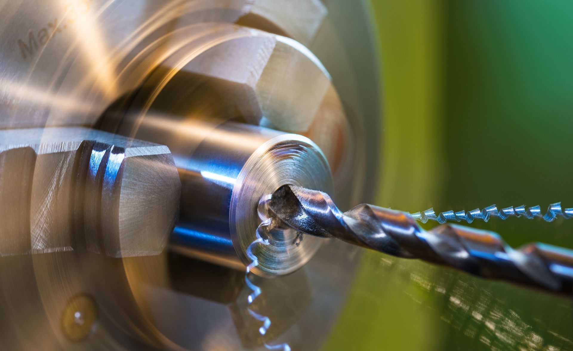 A drill is cutting a hole in a piece of metal.