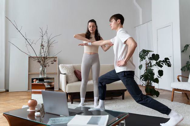 A person performs a lunge in a living room while an instructor provides guidance during an online workout session.