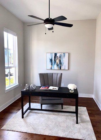 A home office with a desk , chair and ceiling fan.