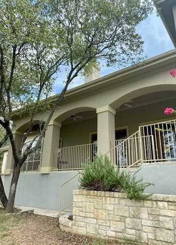 A large house with a large porch and a stone wall.