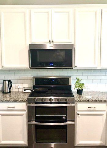 A kitchen with stainless steel appliances and white cabinets.