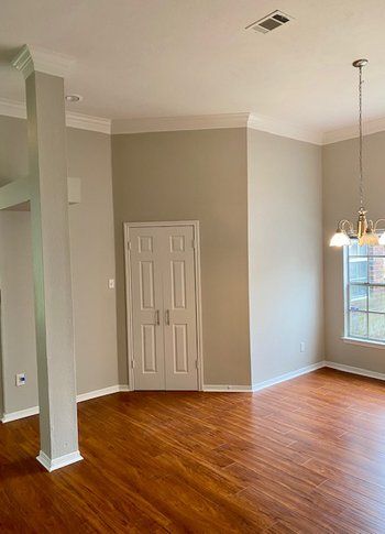 An empty living room with hardwood floors and a door.