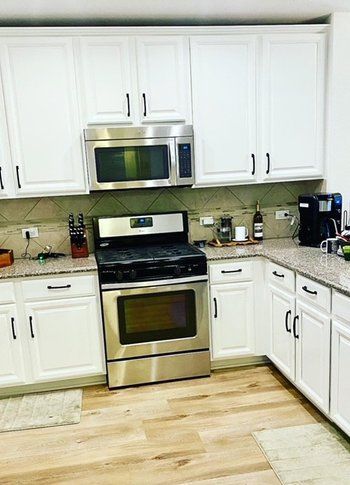 A kitchen with stainless steel appliances and white cabinets.