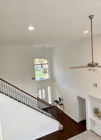 An aerial view of a staircase in a house with a ceiling fan.