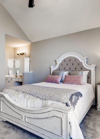 A bedroom with a large bed and a bathroom in the background.