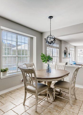 A dining room with a table and chairs in front of a window.
