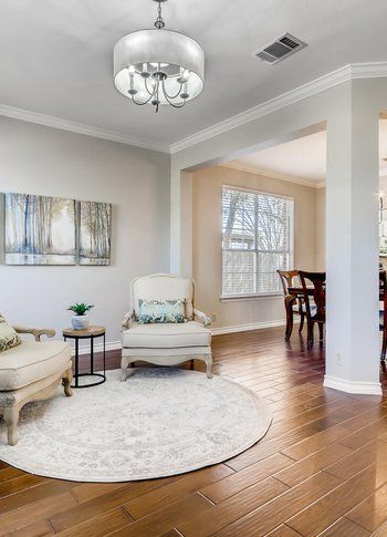 A living room with a chair , rug and chandelier.
