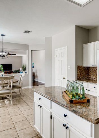 A kitchen with a granite counter top and a tray of bottles on it.