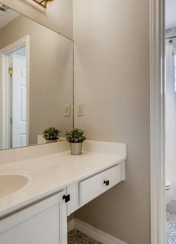 A bathroom with a sink , mirror and drawers.